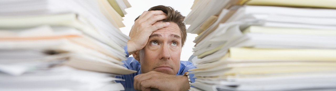 sad man with stacks of documents on the desk