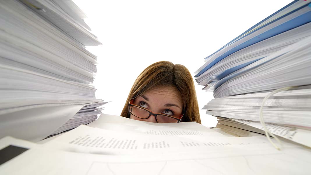 Office girl overwhelmed by piles of documents